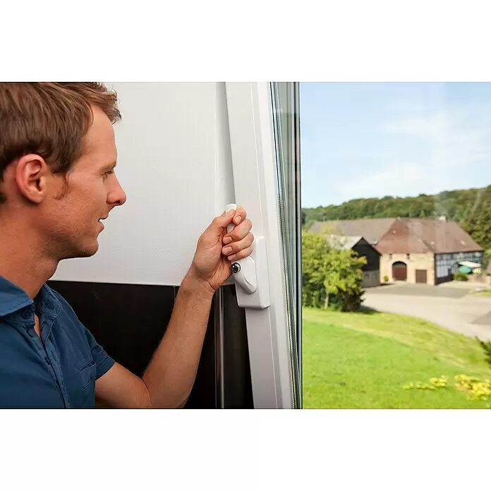 Abus Fenster-Zusatzschloss FO 400 - Dornmaß: 30 mm - 37 mm, Falztiefe: 0 mm - 29 mm, Universell einsetzbar, Weiß - Mann öffnet weißes Fenster mit einem abschließbaren Fenstergriff, Blick auf ländliche Umgebung.
