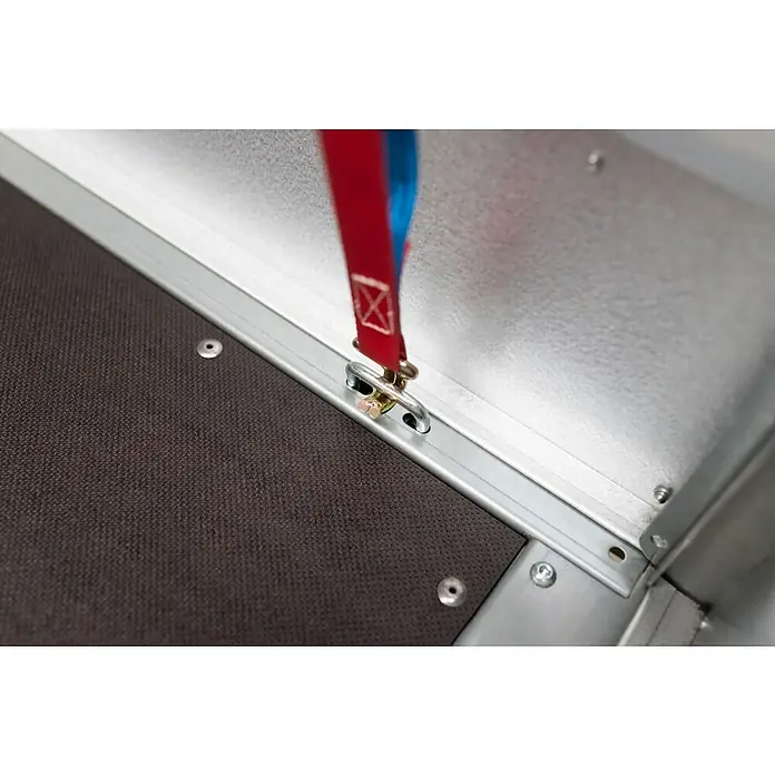 Stema Anhänger Basic STL 7.5-25-13.1 mit Bordwandaufsatz - Nutzlast: 524 kg, Einachser, Kasteninnenmaß: 251 x 128 x 34,5 cm (Höhe inkl. Bordwandaufsatz 69,5 cm), Ungebremst - Nahaufnahme eines Zurrgurts mit rot-blauem Band, befestigt an einem Metalleisen mit goldfarbenen Bolzen, montiert an einer grauen Schiene.
