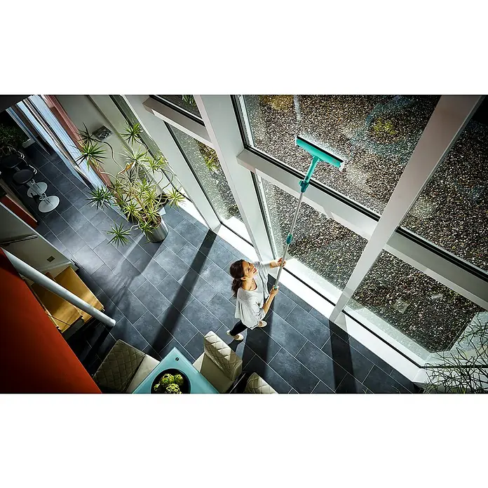 Leifheit Fenster-Wischer Windows & Frame Cleaner L Micro duo - Breite: 32 cm, Kunststoff - Eine Frau putzt mit einem Teleskop-Fensterwischer mühelos hohe Fenster und sorgt für klare Sicht und ein sauberes Zuhause.