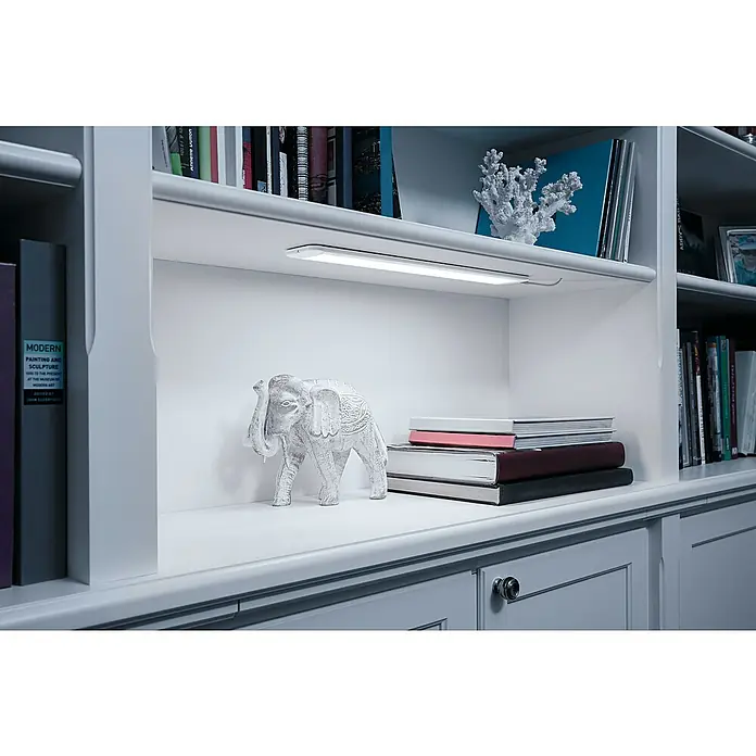 Ledvance Smart+ WiFi LED-Panel Cabinet - L x B x H: 50 x 3,8 x 0,8 cm, 9 W - Diese Aufnahme zeigt eine LED-Leuchte, die in einem Regal angebracht ist und ein warmes Licht auf die darunter liegenden Gegenstände wirft.