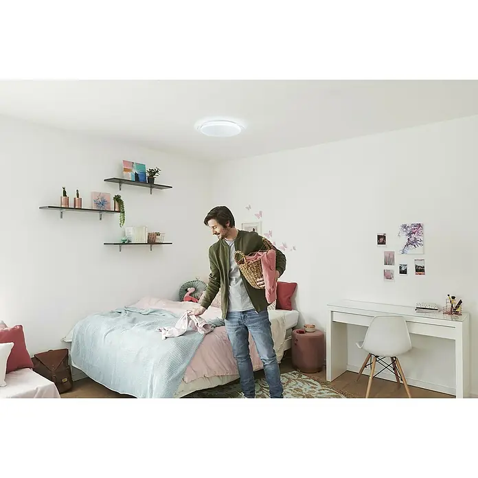 Ledvance LED-Deckenleuchte rund - 24 W, Ø x H: 46 x 7,6 cm, Weiß, Warmweiß - Ein Mann räumt Wäsche in einem hellen Raum auf, beleuchtet von einer modernen Deckenleuchte, die für angenehmes Licht sorgt.