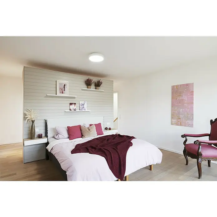 Ledvance LED-Deckenleuchte rund - 28 W, Ø x H: 35 x 9 cm, Weiß, RGBW - Einladendes Schlafzimmer mit einem großen Bett, einer burgunderfarbenen Strickdecke und einem Vintage-Sessel, der eine gemütliche Atmosphäre schafft.