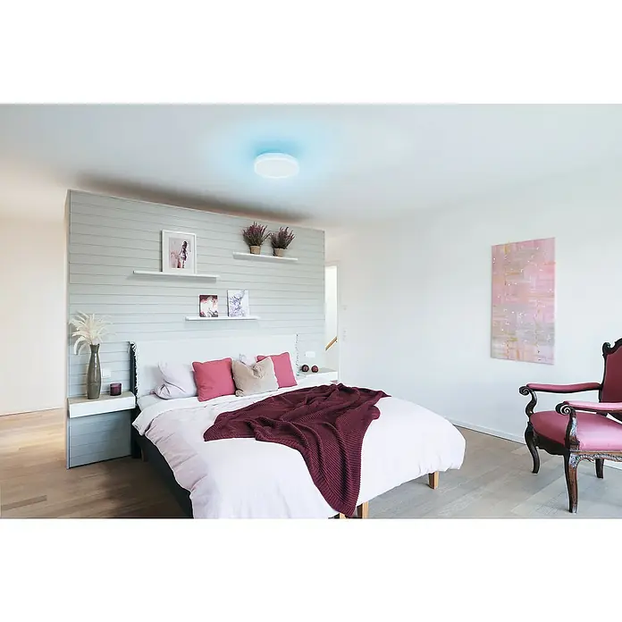 Ledvance LED-Deckenleuchte rund - 28 W, Ø x H: 35 x 9 cm, Weiß, RGBW - Elegante Schlafzimmeraufnahme mit einer modernen LED-Deckenleuchte, die ein sanftes blaues Licht ausstrahlt und für eine beruhigende Atmosphäre sorgt.