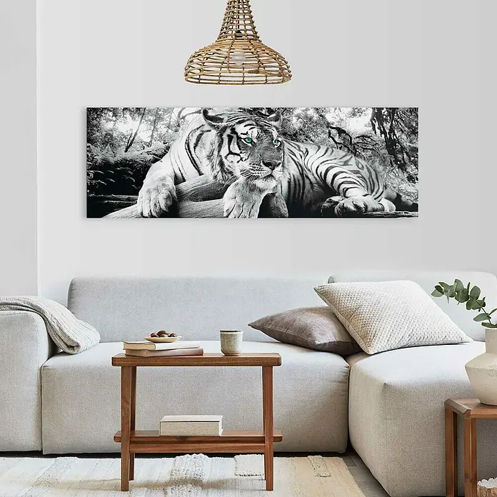 Reinders Decopanel - Tiger is Watching You, B x H: 156 x 52 cm - Ein horizontales Tiger-Wandbild in Schwarz-Weiß, das über einem hellgrauen Sofa in einem modernen Wohnzimmer hängt, akzentuiert den Raum.