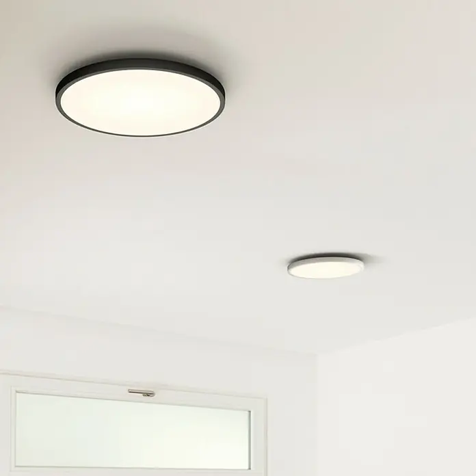 Ledvance LED-Wandleuchte rund32 W, Ø x H: 50 x 4,7 cm, Schwarz, Mehrfarbig - Zwei runde LED-Deckenleuchten in einem hellen Raum. Die größere Leuchte hat einen schwarzen Rahmen.