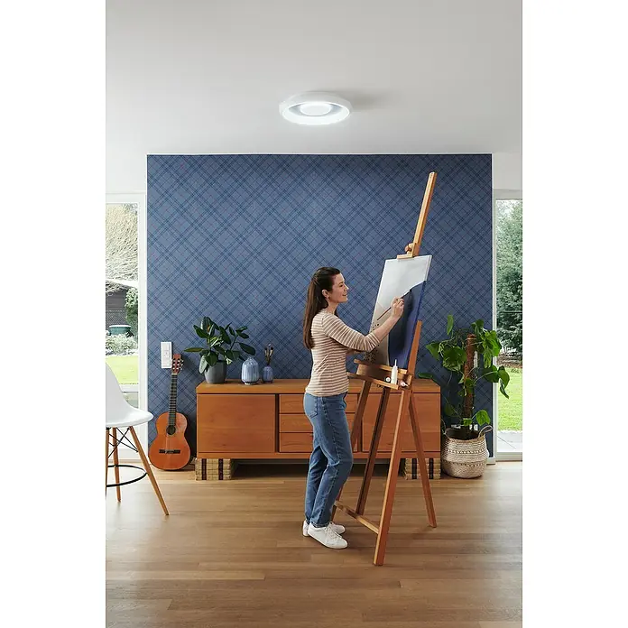 Ledvance LED-Deckenleuchte rund - 32 W, Ø x H: 48,5 x 8 cm, Weiß, Mehrfarbig - Eine Frau malt ein Bild unter einer modernen, runden Deckenleuchte, die den Raum hell erleuchtet.