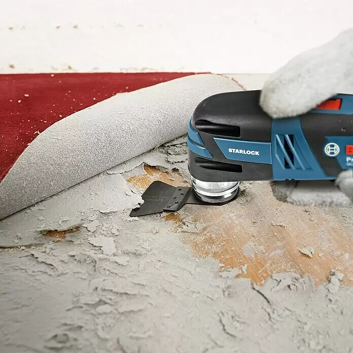 Bosch Professional Akku-Multifunktionswerkzeug GOP 12V-28 - 12 V, Ohne Akku, Ohne L-Boxx - Blau-schwarzes Bosch Multitool mit Schaberaufsatz entfernt weiße Farbe von einer roten Oberfläche, die Holz freilegt.