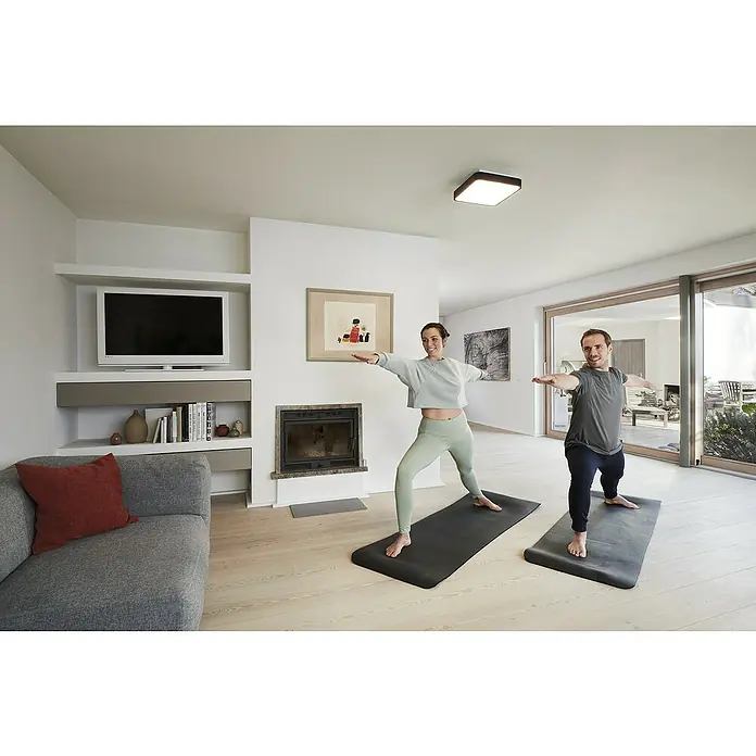 Ledvance LED-Deckenleuchte - 28 W, L x B x H: 35 x 35 x 9 cm, Schwarz, RGBW - Ein Paar macht Yoga in einem hellen Raum mit einer modernen Deckenleuchte, die den Raum gleichmäßig ausleuchtet.
