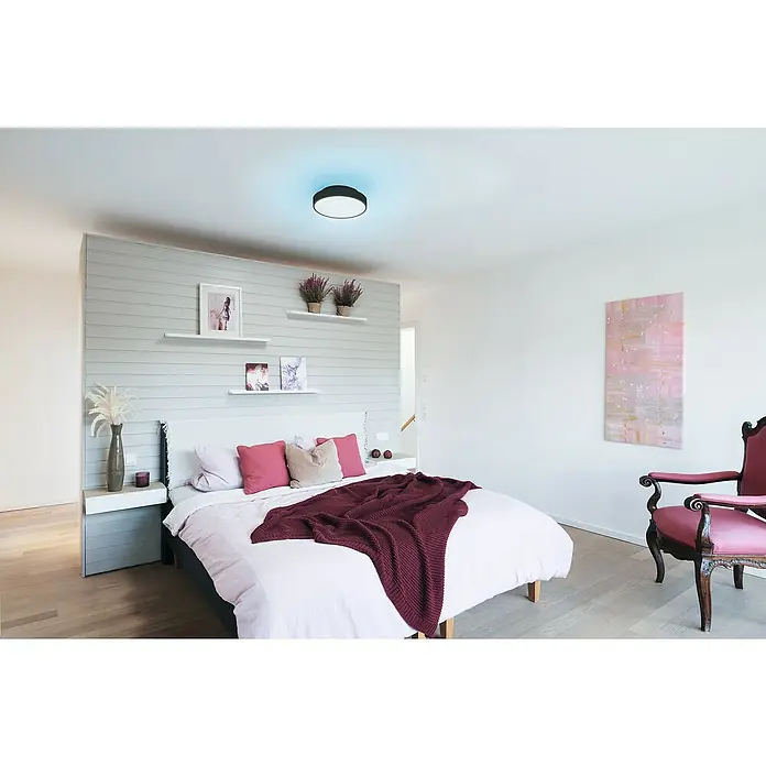 Ledvance LED-Deckenleuchte rund - 28 W, Ø x H: 35 x 9 cm, Schwarz, RGBW - Elegantes Schlafzimmer mit einem modernen schwarzen Deckenleuchte, das ein blaues Licht ausstrahlt, über einem Kingsize-Bett.