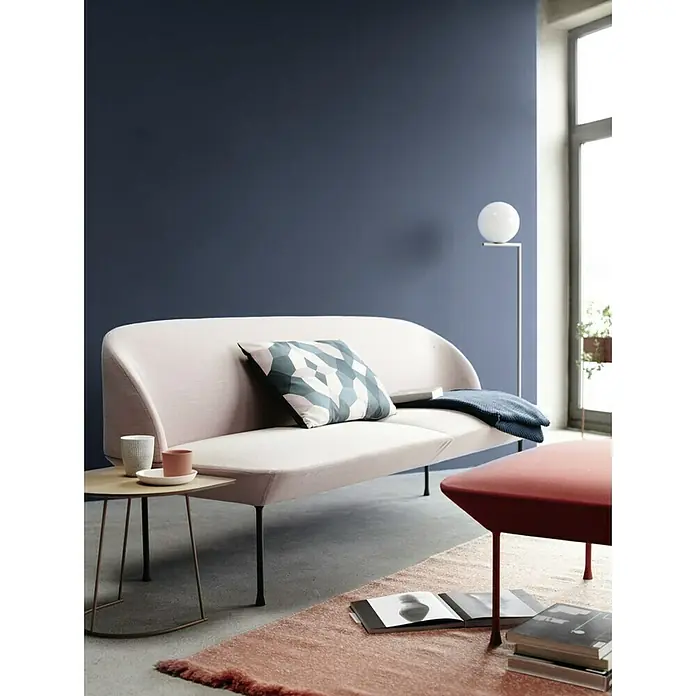 SCHÖNER WOHNEN-Farbe Wandfarbe Trendfarbe - Blueberry, Matt, 1 l, Konservierungsmittelfrei - Elegantes Sofa mit hellrosa Polsterung, geometrischem Kissen und Beistelltisch in einem stilvollen Wohnraum mit blauem Hintergrund.