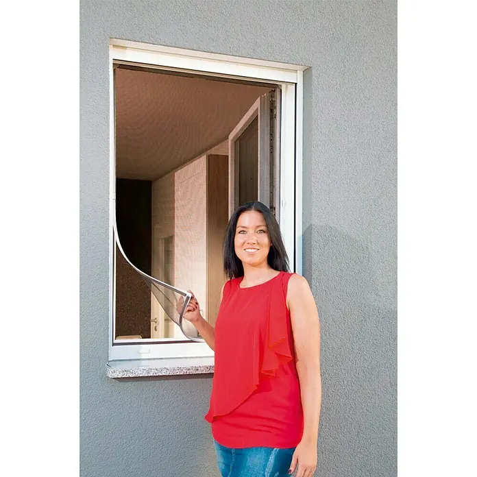 Schellenberg Insect Stop Mosquitera para ventana Magnetic Antipolen - An x Al: 100 x 120 cm, Montaje de la mosquitera: Fijación magnética, Color bastidor: Blanco - Mujer mostrando una mosquitera enrollable para ventanas. La mosquitera es blanca y la malla es fina.