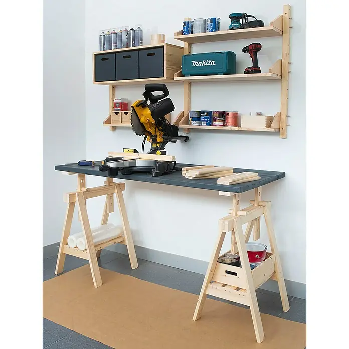 Astigarraga Wally Estante de madera - L x An x Al: 17 x 80 x 14,2 cm, Natural, Madera maciza de pino, Carga límite balda: 100 kg - Escena de taller con una sierra de tronzar sobre un banco de trabajo con caballetes ajustables delante de una pared con estantes.