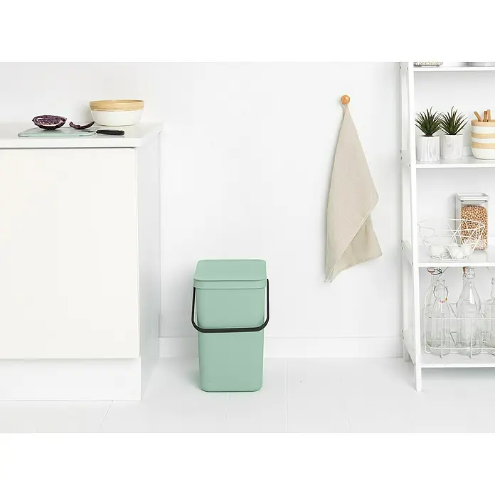 Brabantia Cubo de basura empotrado Sort & Go - 25 l, Verde, Plástico - Un cubo de compost verde menta con asa negra en una cocina moderna con armario blanco y estanterías.