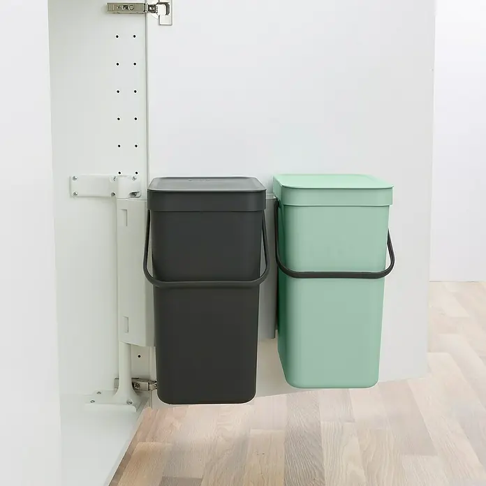 Brabantia Cubo de basura empotrado Sort & Go - 24 l, Plástico, Verde/Negro - Dos cubos de basura, uno en antracita y otro en verde menta, están colocados junto a un armario blanco.