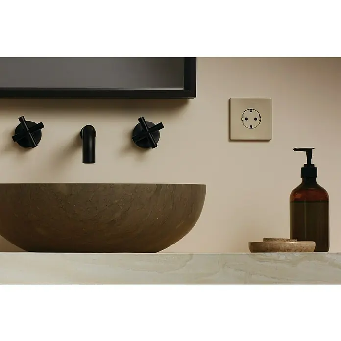 Simon 270 Enchufe Kit - Blanco, 16 A, Colocar - Interior de baño moderno con un elegante lavabo de piedra y un dispensador de jabón oscuro sobre una encimera de mármol.