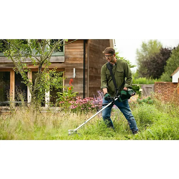 Bosch Power for All 36V Akku-Rasentrimmer AdvancedGrassCut 36V-33 - 36 V, Li-Ionen, Ohne Akku - Ein Mann benutzt einen Bosch Akku-Rasentrimmer im Garten, um hohes Gras zu schneiden. Der Rasentrimmer ist mit einem Schultergurt ausgestattet.