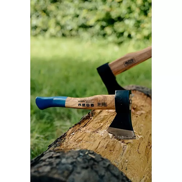 Alpha Tools Handbeil - 600 g - Blau-holzfarbene Axt mit schwarzem Kopf in einem Holzscheit, Späne sichtbar. Eine weitere Axt im Hintergrund.