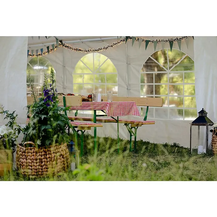 Sunfun Partyzelt - B x T: 396 x 600 cm, Farbe Dach: Weiß - Ein rustikaler Biertisch mit rot-weiß karierter Decke unter einem Festzelt, dekoriert mit Blumen und Lichtern für eine einladende Atmosphäre.