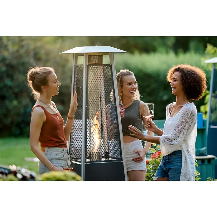 Terrassenstrahler Kairo - 10 kW, Höhe: 182 cm - Eine Gruppe von Frauen steht um einen stilvollen Terrassenheizer, der Wärme und Atmosphäre in ihren Garten bringt. Sie genießen die Zeit im Freien.