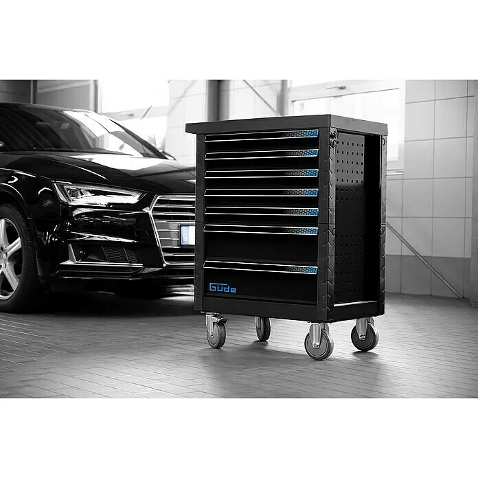 Güde Werkstattwagen GW Black Line - 226 -tlg., B x T x H: 793 x 460 x 980 mm, Anzahl Schubladen: 7 Stk. - Schwarzer mobiler Werkstattwagen mit blauen Akzenten und Güde-Logo, in einer Werkstatt neben einem schwarzen Auto.
