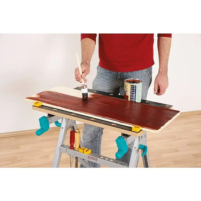 Wolfcraft Master Werkbank Master 200 - Arbeitshöhe: 800 mm, Belastbarkeit: 180 kg - Lackieren einer Holzplatte mit rotbraunem Lack auf einer Wolfcraft Werkbank.