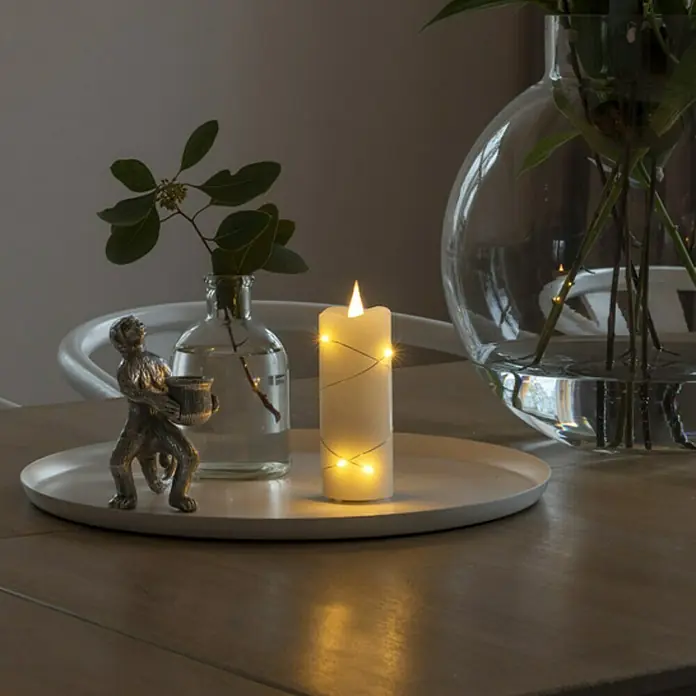 Konstsmide LED-Echtwachskerze - Ø x H: 5 x 12,7 cm, Creme - Nahaufnahme einer LED-Echtwachskerze mit zarten Lichtern, die eine warme, gemütliche Atmosphäre schaffen.