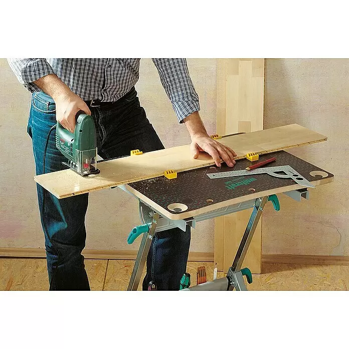 Wolfcraft Master Werkbank Master 600 - Arbeitshöhe: 950 mm, Belastbarkeit: 120 kg - Person sägt eine Holzplatte auf einer mobilen Werkbank mit brauner gemusterter Arbeitsplatte und silbernem Gestell.