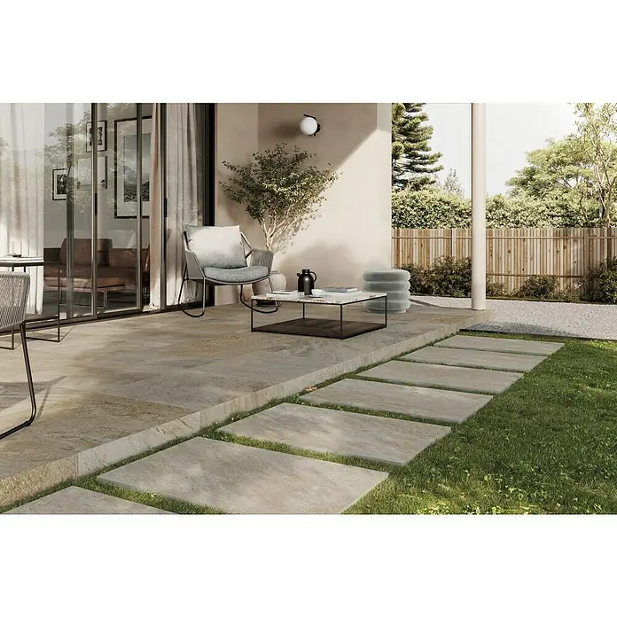 Atlas Concorde Solution Regent Terrassenfliese Ivory - 60 x 60 x 2 cm, Beige/Braun, Matt - Außenaufnahme eines modernen Terrassenbereichs mit beigen Steinplatten, Gartenmöbeln und üppigem Grün, der eine entspannende Atmosphäre schafft.