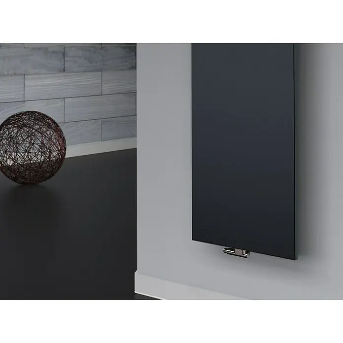 Szagato Designheizkörper Manhattan 3 - B x H: 470 x 1.800 mm, Wärmeleistung bei Vorlauftemperatur von 75 °C (D: 50): 1.118 W, Anthrazit, Mit 2 Handtuchhalter (50 mm) - Eine Nahaufnahme eines eleganten schwarzen Heizkörpers an einer grauen Wand, ergänzt durch eine dekorative Kugel auf einer schwarzen Oberfläche.