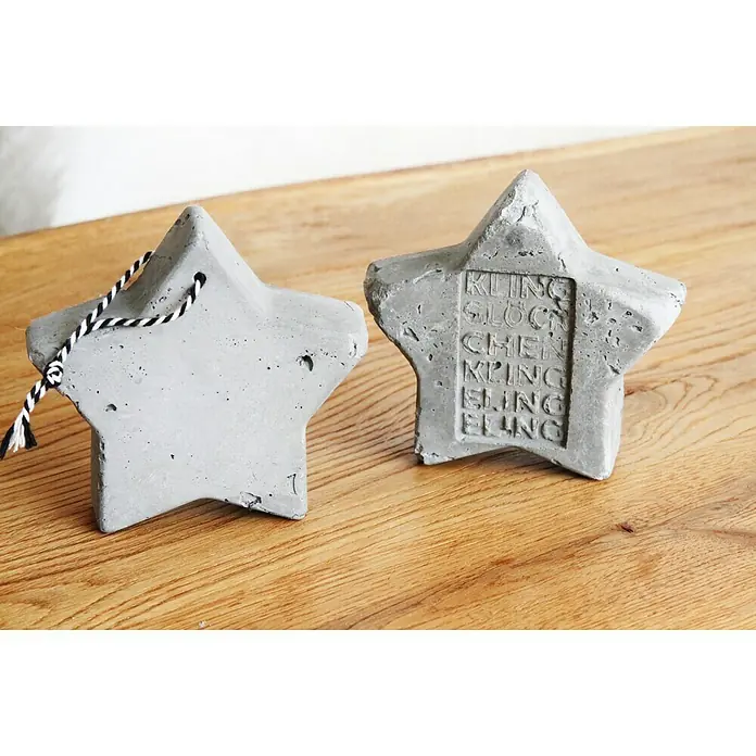 Ultrament Beton-Gießmasse Bastel Beton - Hellgrau, 1,5 kg - Zwei graue Betonsterne, einer mit einer Schnur und einer mit dem Text „KLING GLÖCKCHEN KLINGELING“.