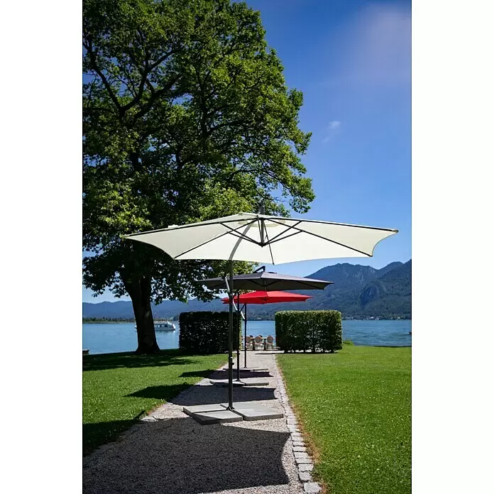 Sunfun Ampelschirm Toscana - Chili, Durchmesser Bespannung: 300 cm - Ein hellfarbener Sonnenschirm steht am See, weitere Schirme spenden Schatten an einem sonnigen Tag.