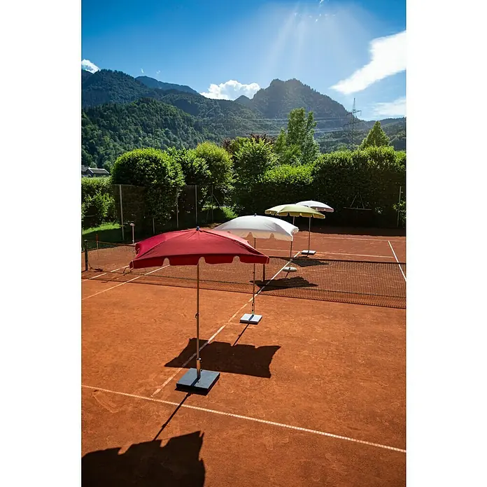 Sunfun Balkonschirm Messina II - Taupe, Bespannungsmaß (L x B): 180 x 120 cm - Drei Sonnenschirme in Rot, Weiß und Gelb auf einem Tennisplatz aus roter Erde bieten Schatten und Schutz vor der Sonne.