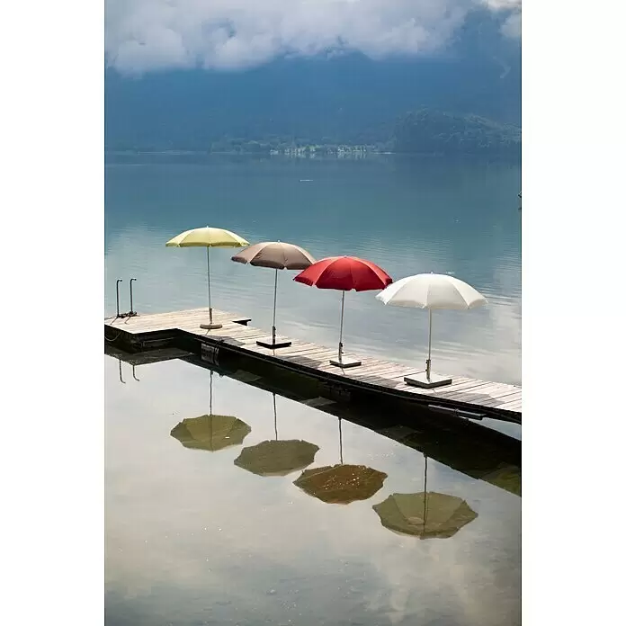 Sunfun Balkonschirm rund Provence II - Chili, Durchmesser Bespannung: 200 cm - Vier bunte Sonnenschirme (gelb, braun, rot, weiß) stehen auf einem Holzsteg am Seeufer, spiegeln sich im Wasser, Berge im Hintergrund.
