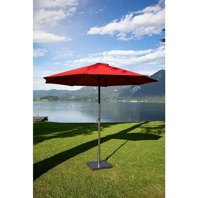 Sunfun Marktschirm Trentino II - Chili, Durchmesser Bespannung: 300 cm - Ein roter quadratischer Sonnenschirm steht auf einem grünen Rasen mit einem See und Bergen im Hintergrund.