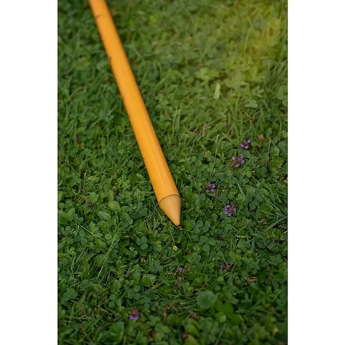 Sunfun Strandschirm - Gelb/Orange, Durchmesser Bespannung: 180 cm - Detailaufnahme eines gelben Erdpfahls, der in einem grünen Rasen steckt, ideal für Gartenbau- oder Landschaftsbauprojekte.
