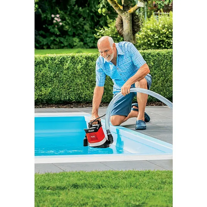AL-KO Premium Tauchpumpe Twin 1100 - 850 W, Max. Fördermenge: 13.000 l/h - Mann, der eine AL-KO-Tauchpumpe zum Entleeren eines Pools verwendet, mit einem grünen Garten im Hintergrund.