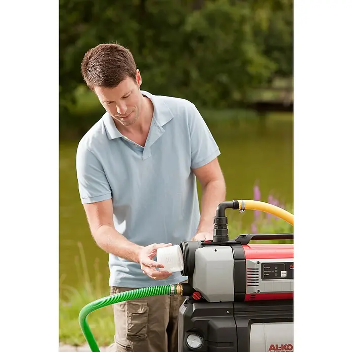 AL-KO FilterPassend für: AL-KO Pumpen Jet F/HW F/HWA F - Ein Mann wartet eine AL-KO Hauswasserwerk-Pumpe, die in einem Garten in der Nähe eines Teiches steht.