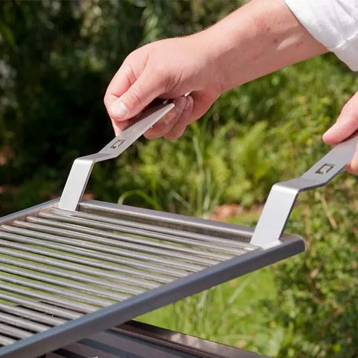 oneQ Grillbesteck - Länge: 21,5 cm - Nahaufnahme einer Person, die mit einem Paar Grillheber einen Grillrost anhebt. Die Heber sind aus Metall.