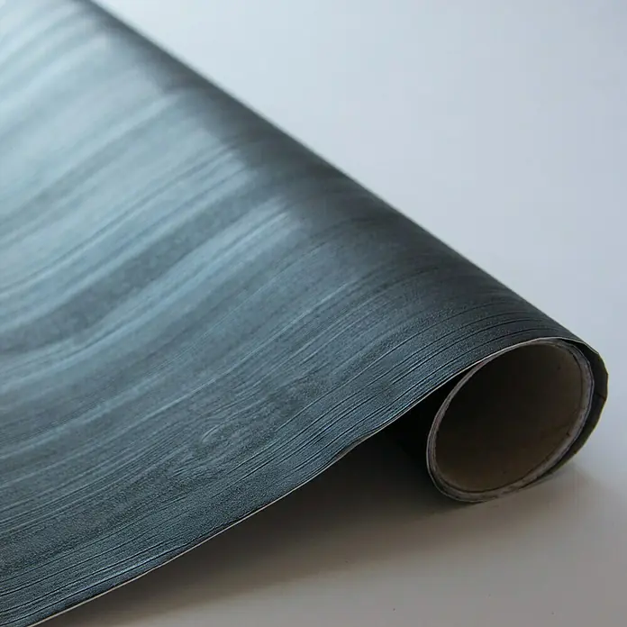D-c-fix Lámina efecto madera Quadro - 150 x 67,5 cm, Negro, Autoadhesivo - Primer plano de un rollo de vinilo oscuro autoadhesivo con aspecto de madera.