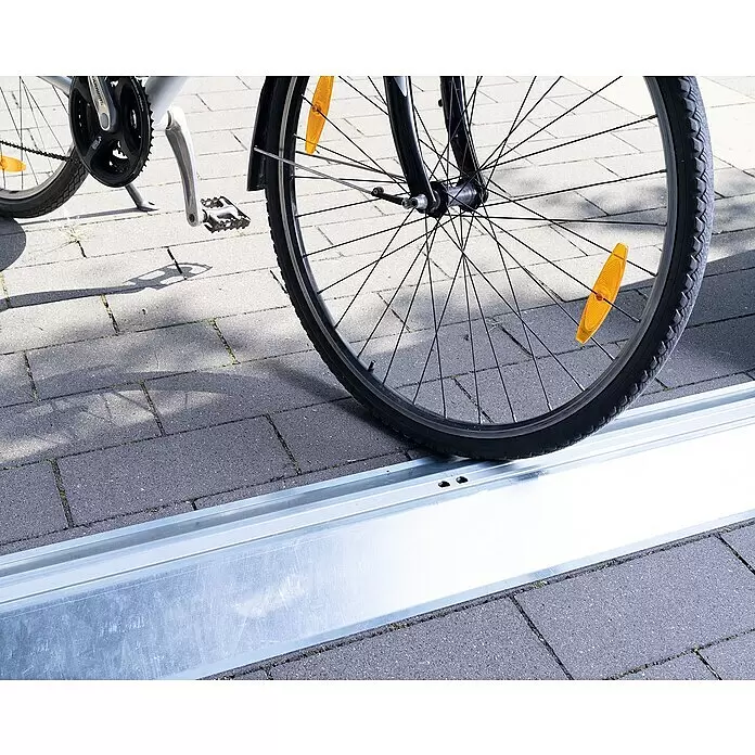 EcoStar Bodenschwellen-Rampe - Passend für: EcoStar Gerätehäuser mit Doppeltür, Innen - Silberne Metall-Fahrradparkschiene, in der ein Vorderrad eines Fahrrads gesichert ist.