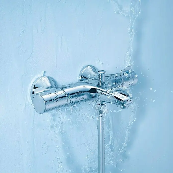 Grohe Wannenthermostat - Chrom, Glänzend - Nahaufnahme einer verchromten Duscharmatur, an der Wasser herunterläuft. Der Fokus liegt auf der Armatur und dem fließenden Wasser.
