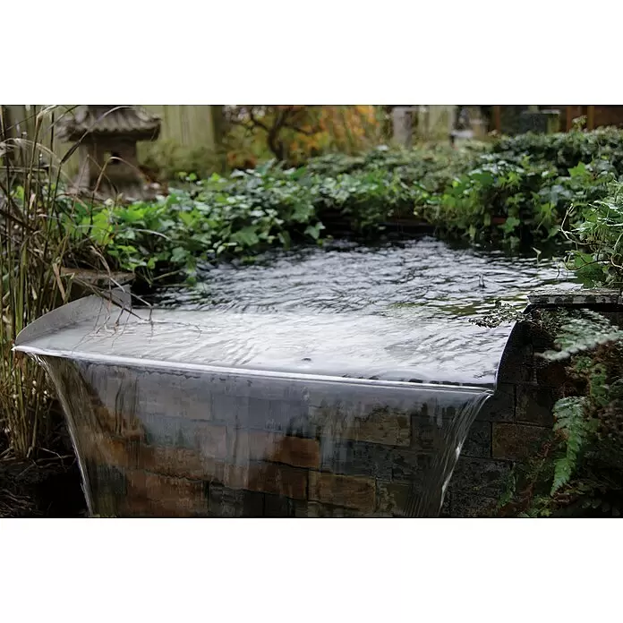 Ubbink Überlauf-Element Brisbane - L x B x H: 25 x 60 x 6 cm - Ein modernes, elegantes Wasserfall-Feature mit einem breiten, kaskadierenden Wasserfall, integriert in einen üppigen Gartenteich mit grünem Laub.