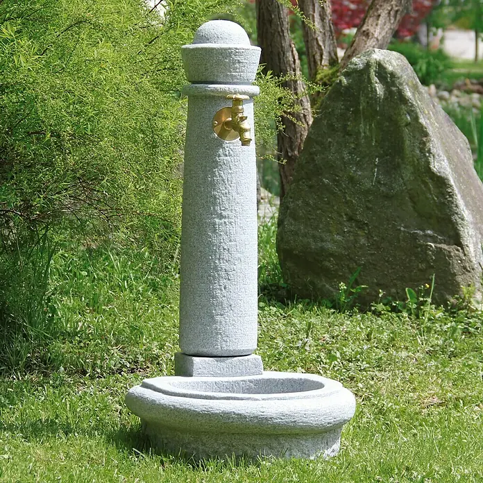 Garantia Brunnen Venezia - Lightgranite, 52 x 44 x 90 cm - Nahaufnahme eines dekorativen Granitbrunnens mit goldenem Wasserhahn in einem Garten.