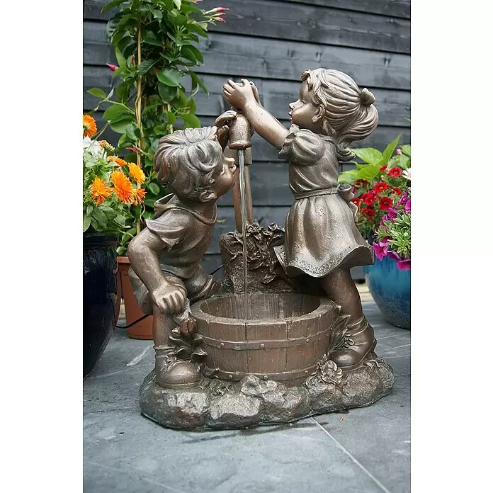 Ubbink AcquaArte Gartenbrunnen Memphis - 26,5 x 47 x 64 cm, Kunststoff, Bronze - Bronzefarbene Brunnen-Skulptur von Kindern an einer Wasserpumpe, Wasser fließt in ein Fass im Garten.
