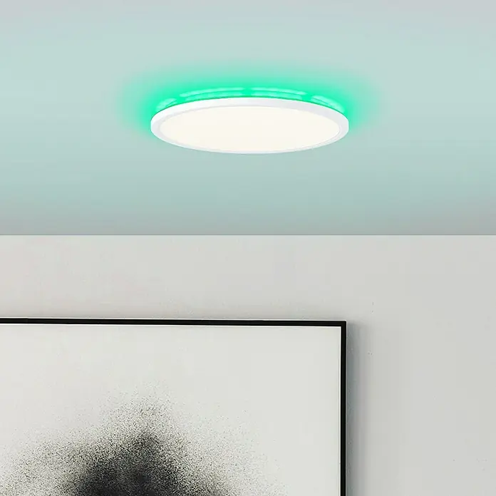 Brilliant LED-Deckenleuchte rund Tanida - 20 W, Ø x H: 29,5 x 2,5 cm, Weiß, Kaltweiß - Nahaufnahme einer runden LED-Deckenleuchte mit weißem Rahmen und grüner Hintergrundbeleuchtung, die in einem modernen Raum installiert ist.