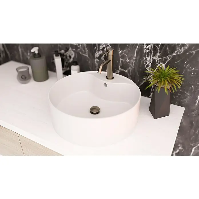 IO Válvula click clack - 1¼'', Níquel - Primer plano de un baño moderno con un lavabo redondo, grifo y elementos decorativos sobre una encimera blanca.