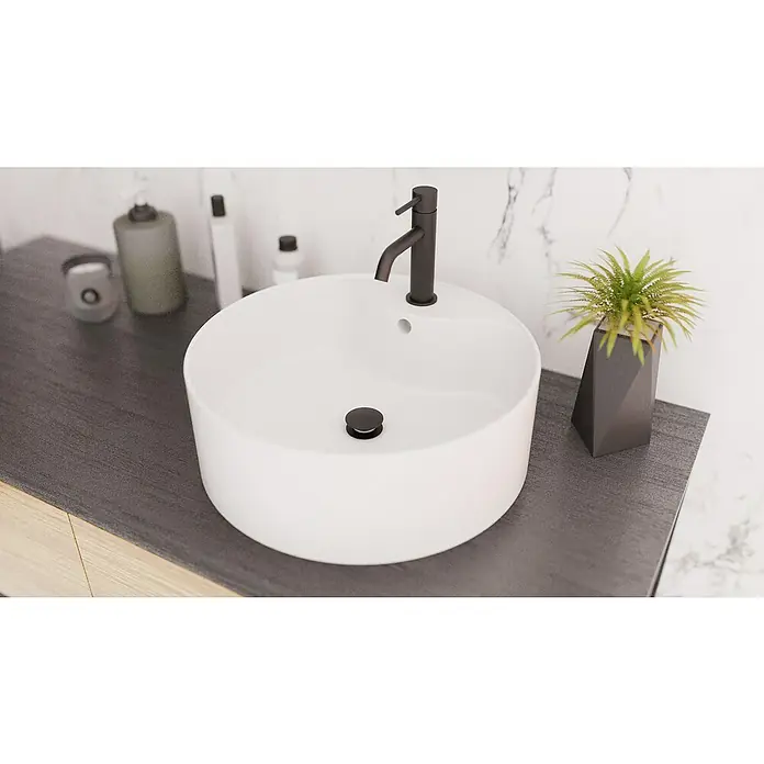 IO Válvula click clack - 1¼'', Negro - Primer plano de un moderno lavabo redondo sobre encimera con grifo negro y decoración minimalista en un baño.