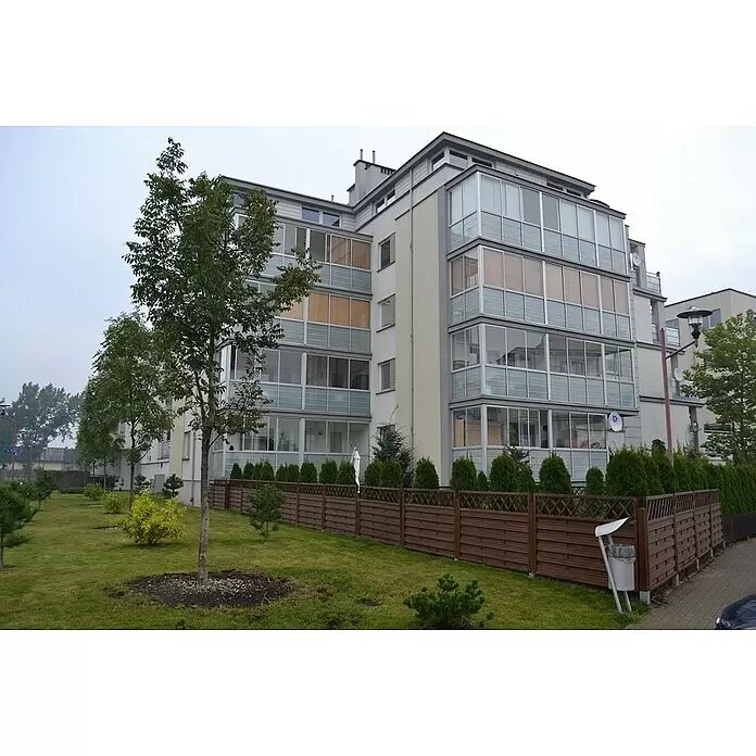 Andrewex Sichtschutzelement Hamburg - Braun - Modernes Apartmenthaus mit Glasbalkonen, umgeben von grünem Rasen, Bäumen und einem Holzzaun.