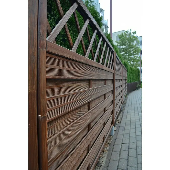 Andrewex Sichtschutzelement Hamburg - Braun - Nahaufnahme eines braunen Holzzauns mit dekorativem Gittermuster, der einen Gartenweg säumt und Privatsphäre bietet.