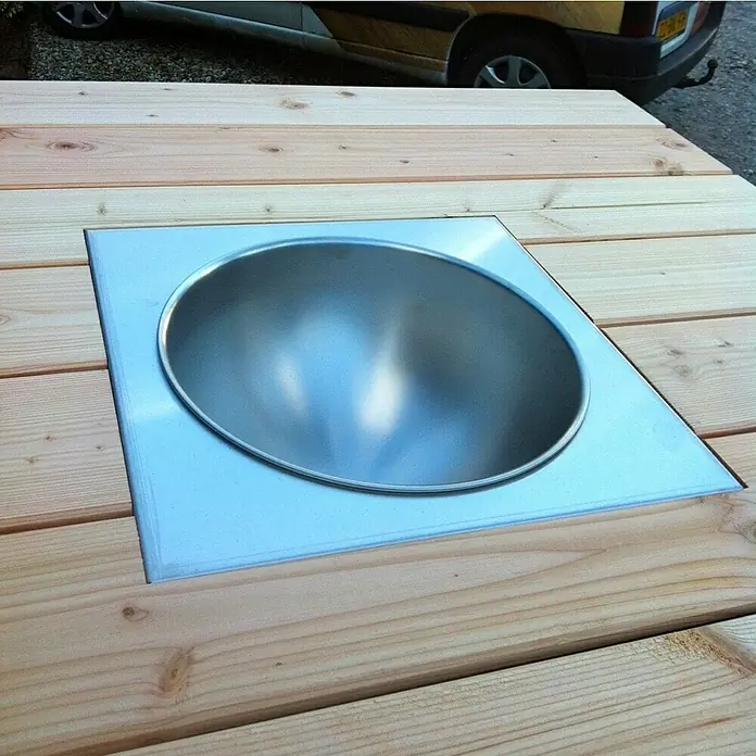 oneQ Flaschenkühler - Silber, L x B: 40,7 x 40,7 cm - Nahaufnahme eines eingelassenen, runden Metalleinsatzes in einer hellen Holzoberfläche, der eine moderne Ästhetik erzeugt.